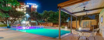 A pool with a table and chairs in front of a building.